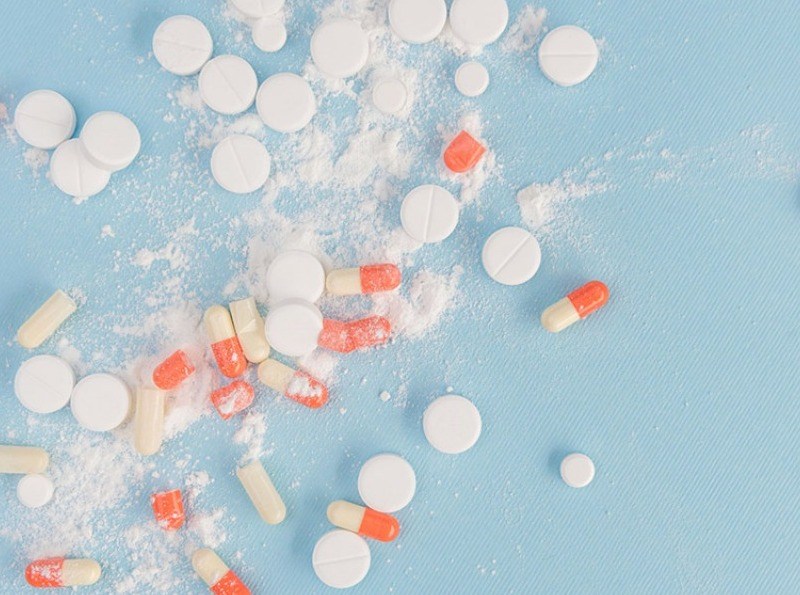 Broken white different size tablets and capsules on a blue background